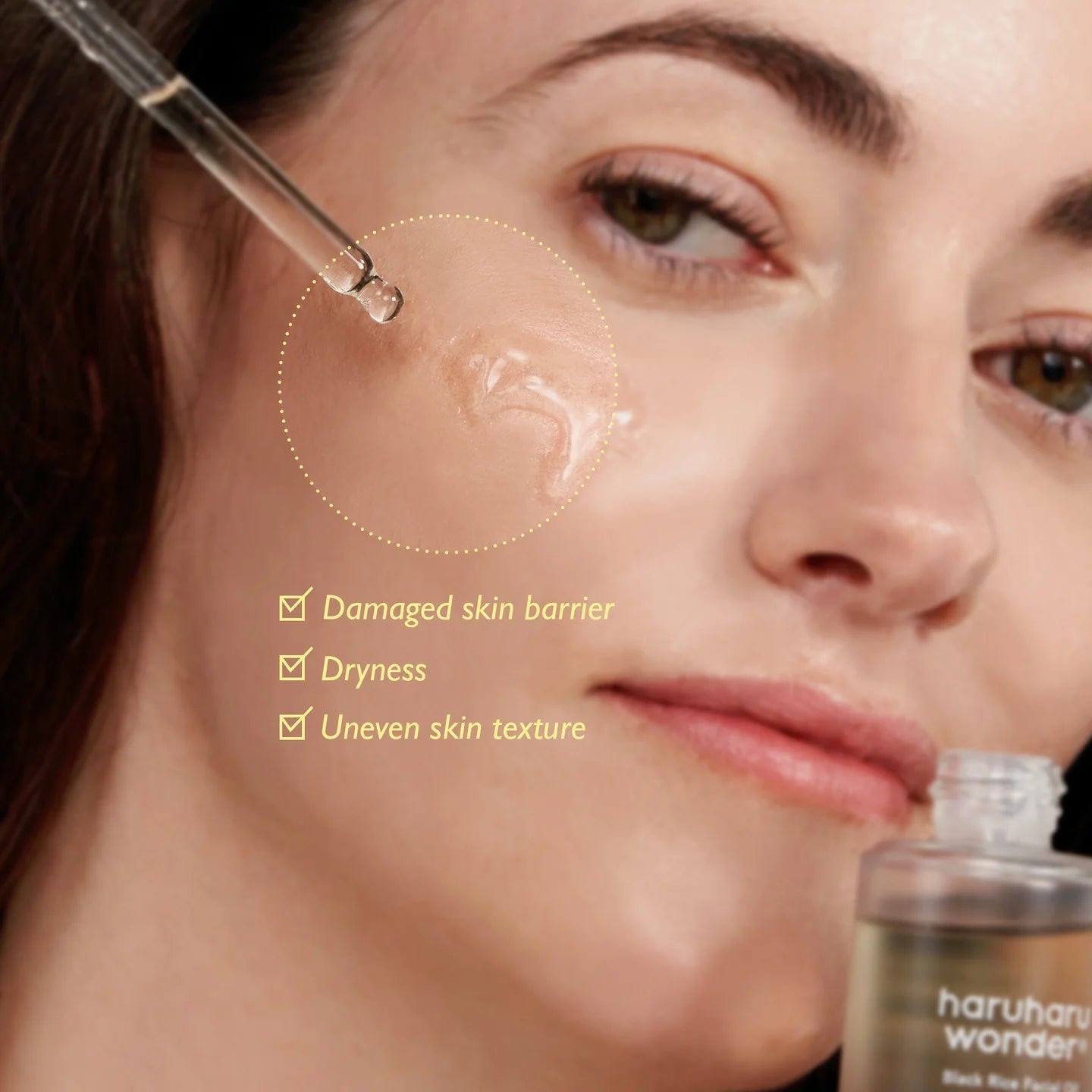 Haruharu Wonder Black Rice facial oil model applying drops to cheek - Overrated Korean Beauty & More